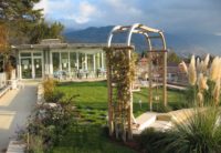 a photo of a wooden archway in the garden at the top of roches grises with mountains in the background