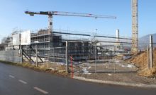 scaffolding surrounding the praz-dagoud campus under construction behind a fence