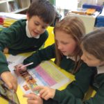 three students working together on an ipad to fill in a work sheet